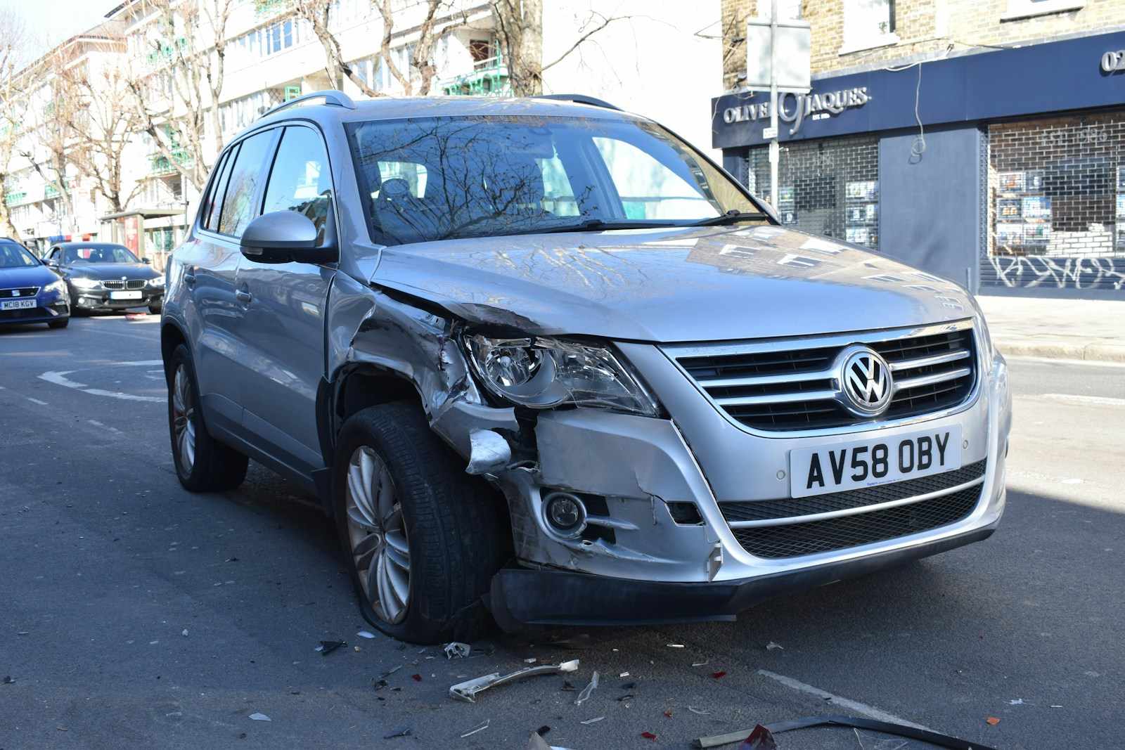 Uszkodzony przód srebrnego SUV-a po kolizji na miejskiej ulicy